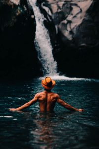 Man in hat in a waterfall